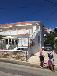 a group of people standing in front of a house at Apartmani Denona Centar in Novalja