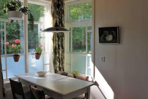 a table and chairs in a room with windows at B&B Appartement De Winkeljuffer in Bakkeveen