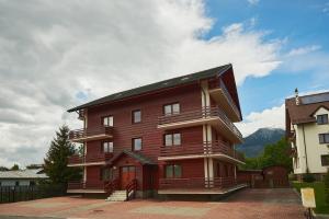 a large red building with a black roof at Holiday apartment High Tatras in Vysoke Tatry - Tatranska Lomnica.