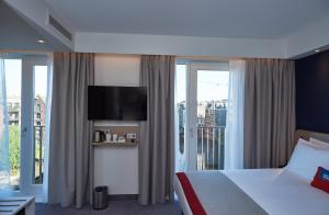 a hotel room with a tv and a balcony at Holiday Inn Express Amsterdam - City Hall, an IHG Hotel in Amsterdam