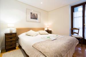 um quarto com uma grande cama branca e uma cadeira em Txoriak - Basquenjoy em Hondarribia