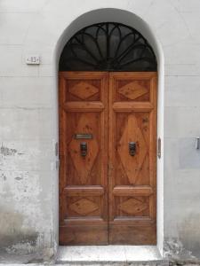 - une porte en bois dans un bâtiment blanc avec une arche dans l'établissement Solo per Noi Apartment, à Sienne
