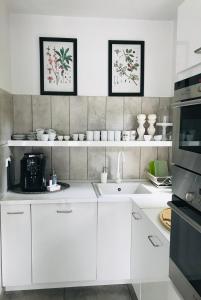 a kitchen with white cabinets and white appliances at Pastel Guesthouse in Balatonfüred