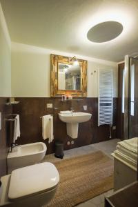 bagno con lavandino, servizi igienici e specchio di La Maison Du Lac Iseo a Predore