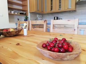 un cuenco de cerezas sentado sobre una mesa de madera en Apartments Mas en Dovje