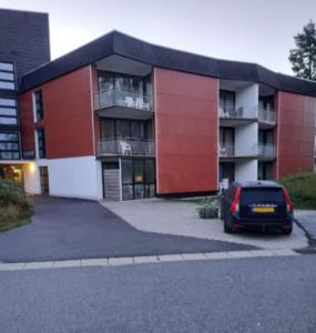 czerwony budynek z parkingiem w obiekcie Appartement Altreichenau w mieście Neureichenau