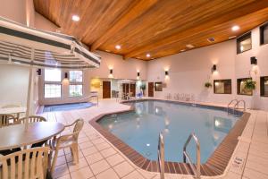 una piscina en una habitación de hotel con mesa y sillas en Kelly Inn and Suites Mitchell en Mitchell