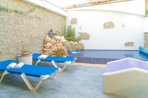 un patio con sillas azules y una piscina en La Pausa Rural & Wellness, en Santa Greu del Jutglar