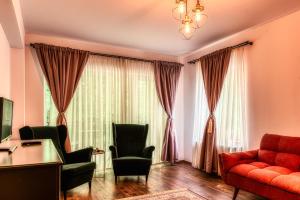 a living room with a red couch and chairs at Nature Apartment - Minutes Away from the Old Town and AFI Mall in Braşov