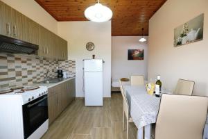 a kitchen with a table and a white refrigerator at Fergani Apartments in Moudhros