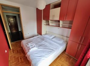 a bedroom with red cabinets and a bed with white sheets at Fushe Kosove Apartments in Pristina