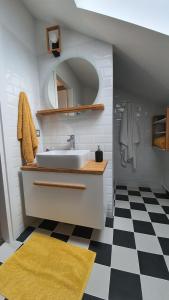 a bathroom with a sink and a mirror and a checkered floor at Marmot apartment up & down in Poiana Brasov