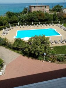 an empty swimming pool with lounge chairs and the ocean at Residence Pietre Bianche ApartHotel in Pizzo
