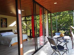 
a room with a bed, table, chairs and a window at La Guayaba Monteverde in Monteverde Costa Rica
