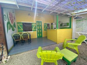 Zimmer mit gelben und grünen Stühlen und einem Tisch in der Unterkunft Gites titanse, Le jardin d'Antonin in Cadet