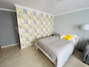 sypialnia z białym łóżkiem i żółtą ścianą w obiekcie Apartament na Starówce III w Pszczynie