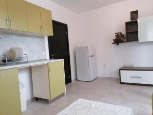 a kitchen with yellow cabinets and a white refrigerator at Complex Argo ap.2 in Ravda