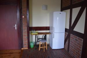 a refrigerator in a room with a table and a stool at Pensjonat pod Kasztanem in Ełk