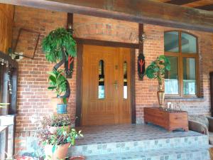 a brick house with a wooden door and potted plants at Pensjonat pod Kasztanem in Ełk