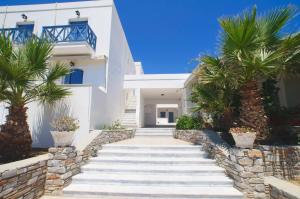 a staircase leading to a white house with palm trees at Manos Apartments in Megas Yialos-Nites