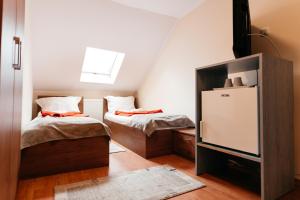 Habitación pequeña con 2 camas y nevera. en Pension Rose-Trandafirul, en Borsec