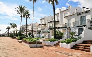 una fila de edificios de apartamentos blancos con palmeras en Costa del Sol, Puerto de la Duquesa, en Castillo de Sabinillas