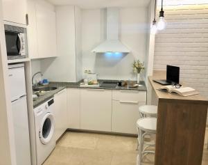 a kitchen with white cabinets and a laptop on a counter at Mediterraneo Sitges in Sitges