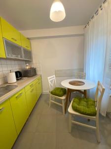 クドヴァ・ズドゥルイにあるApartament CamInSkiのキッチン(黄色のキャビネット、テーブル、椅子付)