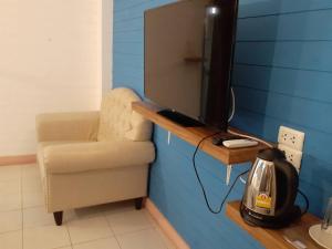 Habitación con silla y mesa con TV. en Infinite Hotel en Bangkok