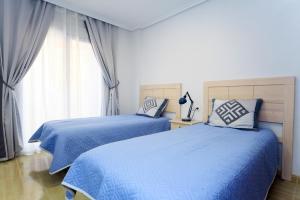 1 dormitorio con 2 camas con sábanas azules y ventana en Two Bedroom Apartment La Manga en La Manga del Mar Menor