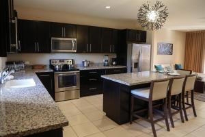 a kitchen with black cabinets and a kitchen island with bar chairs at Coco Breeze Pacific in Coco