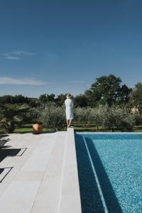 una persona in piedi sul bordo di una piscina di Heritage Hotel San Rocco a Brtonigla (Verteneglio)