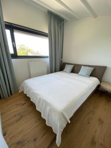 ein großes Bett in einem Zimmer mit einem großen Fenster in der Unterkunft Welcome in - Lepelblad 44, Nieuwvliet in Nieuwvliet