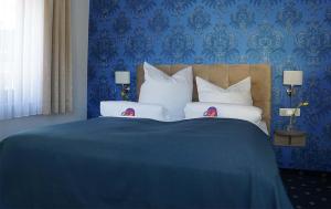 ein blaues Schlafzimmer mit einem Bett mit zwei Puppen drauf in der Unterkunft Arthotel Nagold in Nagold