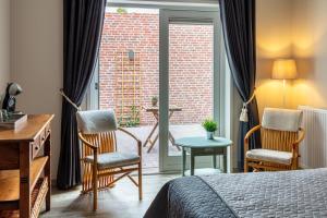 a hotel room with a bed and two chairs and a window at Herberg Binnen in Egmond-Binnen