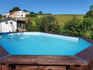 einen großen Pool mit einer Holzterrasse und einem blauen Pool in der Unterkunft 2 vraies chambres privées au calme dans villa de campagne plain-pied 105m2 avec piscine à Montfaucon in Montfaucon