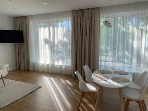 a dining room with a table and chairs and a large window at Apartamentai Fortuna in Kaunas