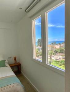 een slaapkamer met 2 ramen met uitzicht op de oceaan bij Hogar en Benicasim in Benicàssim