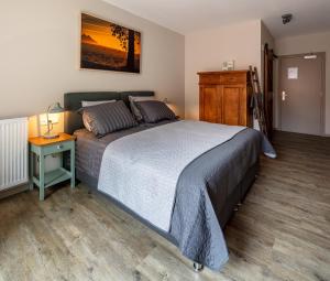 a bedroom with a large bed and a night stand at Herberg Binnen in Egmond-Binnen