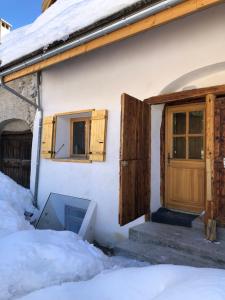 una casa con puerta y ventanas en la nieve en La Maison De Marie, en Le Monêtier-les-Bains