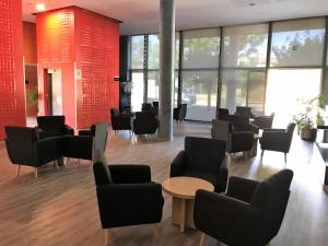 a waiting room with chairs and tables and windows at Holiday Inn Express Molins de Rei, an IHG Hotel in Molins de Rei