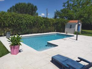 a swimming pool in a yard with a blue chair at Les Agapanthes du frontonnais in Bouloc