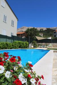 a swimming pool with flowers next to a house at Rooms Nadia3 in Baška