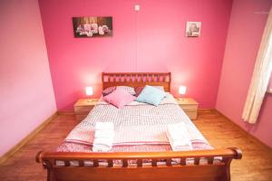 a bedroom with pink walls and a bed with pillows at Voisins du kayak in Dinant