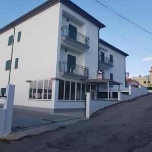 un edificio blanco con balcones en un lateral en Ferrinho, en Guarda