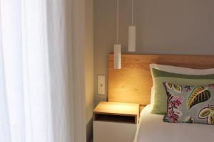 a bed with a wooden headboard next to a window at Cardeal Suites & Apartments in Faro