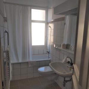 baño con lavabo y aseo y ventana en Hotel De La Paix, en Interlaken
