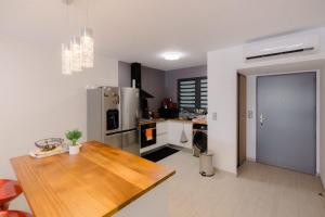 eine Küche mit einem Holztisch und einem Kühlschrank in der Unterkunft Perle bleue résidence in Saint-Leu