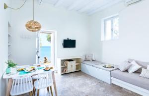 a white living room with a table and a couch at Apothikes Apartments in Koutsounari
