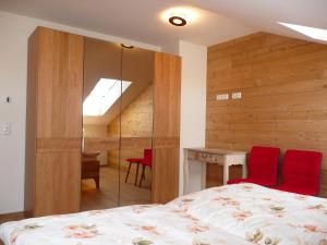 a bedroom with a bed and a desk with red chairs at Alpenstern Ferienwohnung in Pfronten